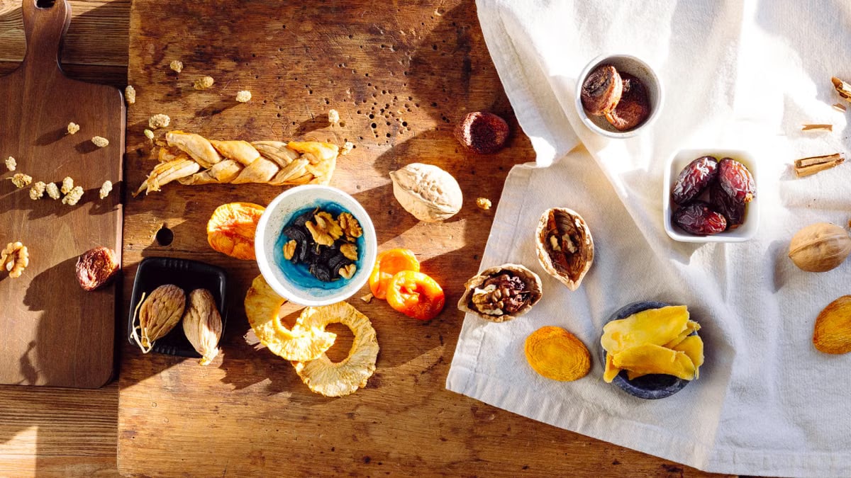 Top view of a rustic assortment of dried fruits and nuts on a wooden board, perfect for healthy snacks.